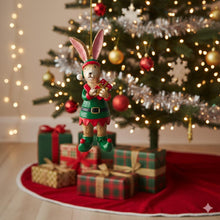 Load image into Gallery viewer, Elf rabbit ornament hanging in front of a decorated Christmas tree with presents underneath.